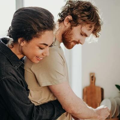 Casal compartilhando um momento íntimo na cozinha, simbolizando a convivência e o vínculo emocional.
