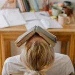 Homem ansioso, sentado em uma mesa com livros e materiais de estudo, simbolizando desafios emocionais e a importância da terapia individual.