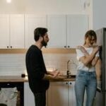 Casal discutindo na cozinha, simbolizando sentimentos de ciúmes e insegurança no relacionamento.