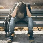 Pessoa sentada em um banco com as mãos cobrindo a cabeça, simbolizando depressão no contexto de terapia individual.
