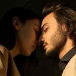 Casal deitado em uma cama, com os corpos virados em direções opostas, simbolizando diferenças de expectativas no relacionamento.