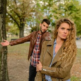 Casal em um parque enfrentando dificuldades para perdoar, simbolizando desafios emocionais em um relacionamento.