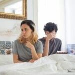 Casal sentado na cama, simbolizando dificuldades emocionais para perdoar no relacionamento.