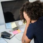 Mulher demonstrando sinais de estresse enquanto trabalha, simbolizando os impactos emocionais do transtorno de estresse pós-traumático (TEPT).
