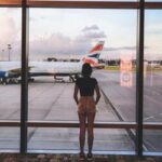 Pessoa em um terminal de aeroporto olhando para um avião, simbolizando a fobia de viajar de avião e o enfrentamento terapêutico.