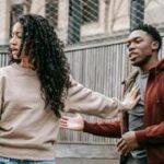 Casal discutindo em um ambiente urbano, simbolizando conflitos e problemas de comunicação no relacionamento.