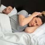Casal deitado em uma cama, simbolizando rotina e desgaste no relacionamento.