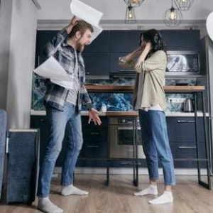 Homem gritando com sua parceira em uma cozinha, simbolizando resolução inadequada de conflitos no relacionamento.